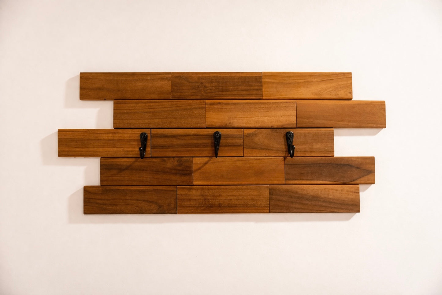 Wooden wall art with horizontal slats and hooks on a white background