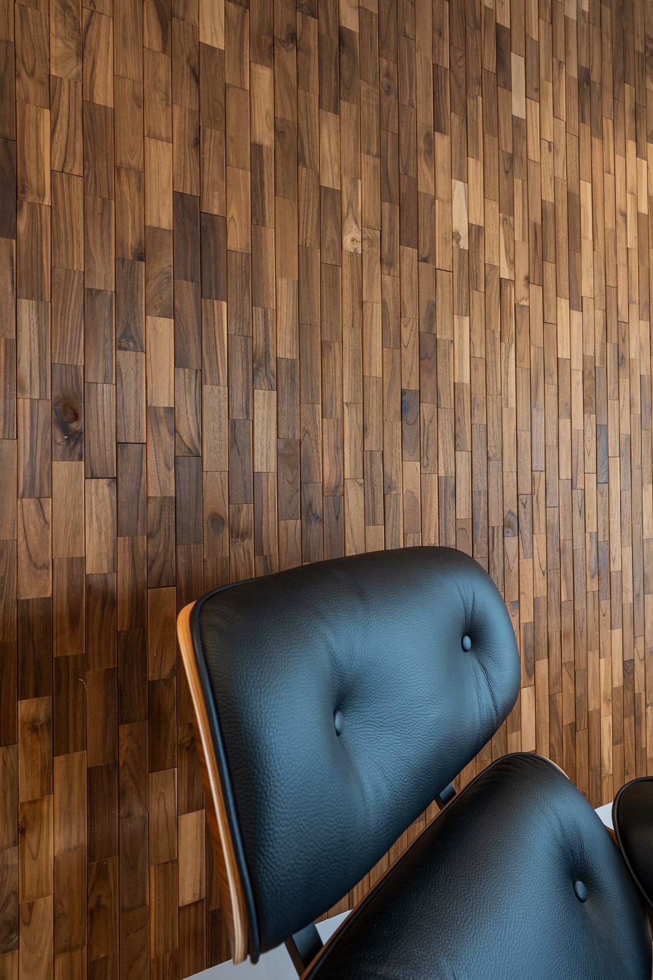 Close-up of Dark teak panel grain behind a leather lounge chair
